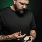 Homem pegando balm para barba com a mão