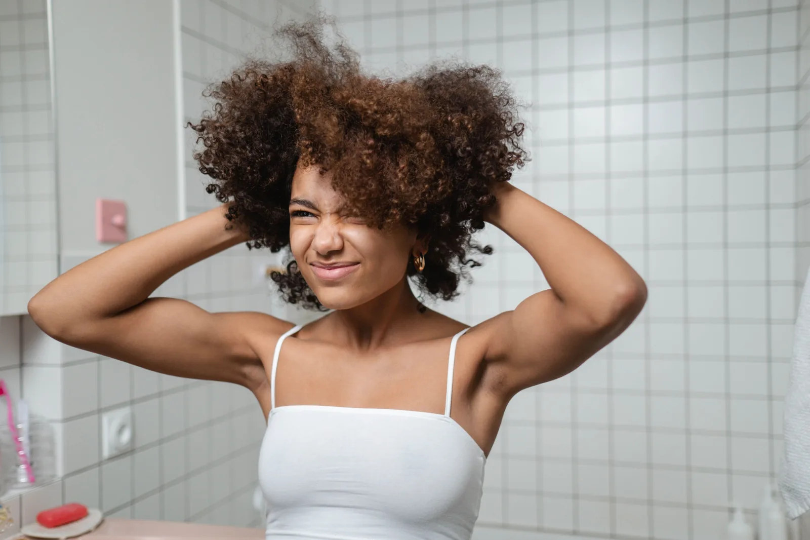 Mulher coçando o cabelo cacheado no banheiro