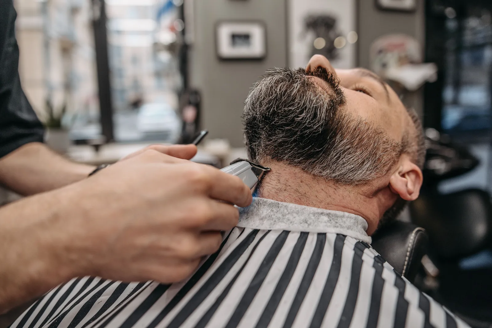 Barbeiro aparando o contorno da barba no cliente