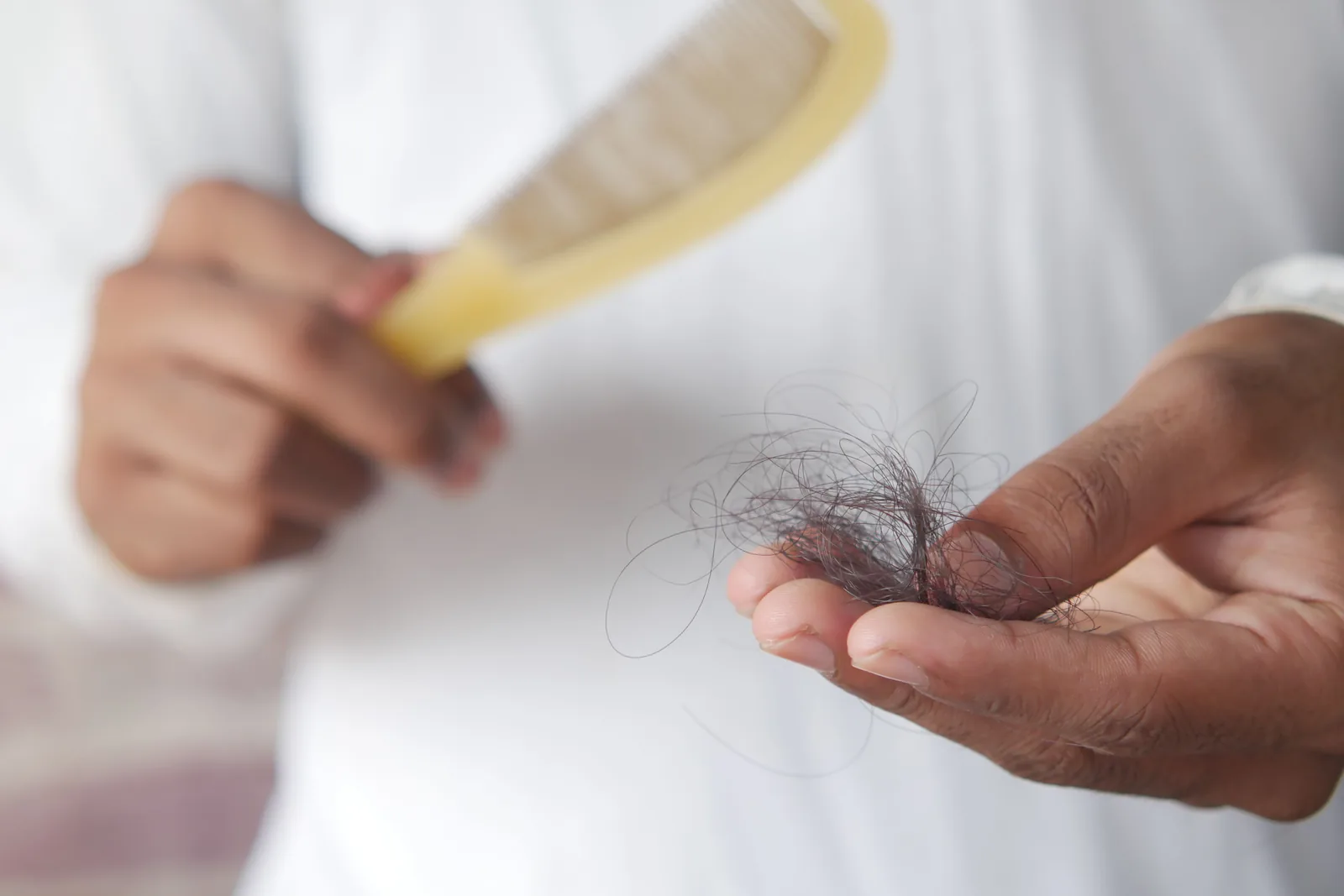 Pente com fios de cabelo caídos na mão