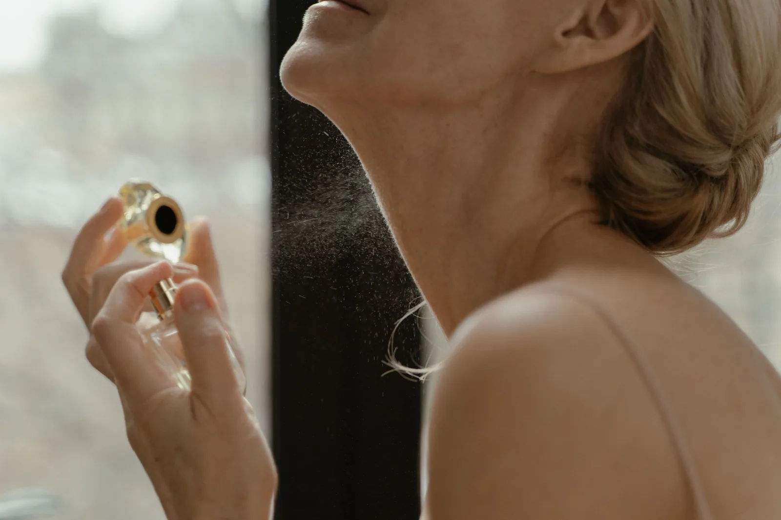 Mulher aplicando perfume no pescoço