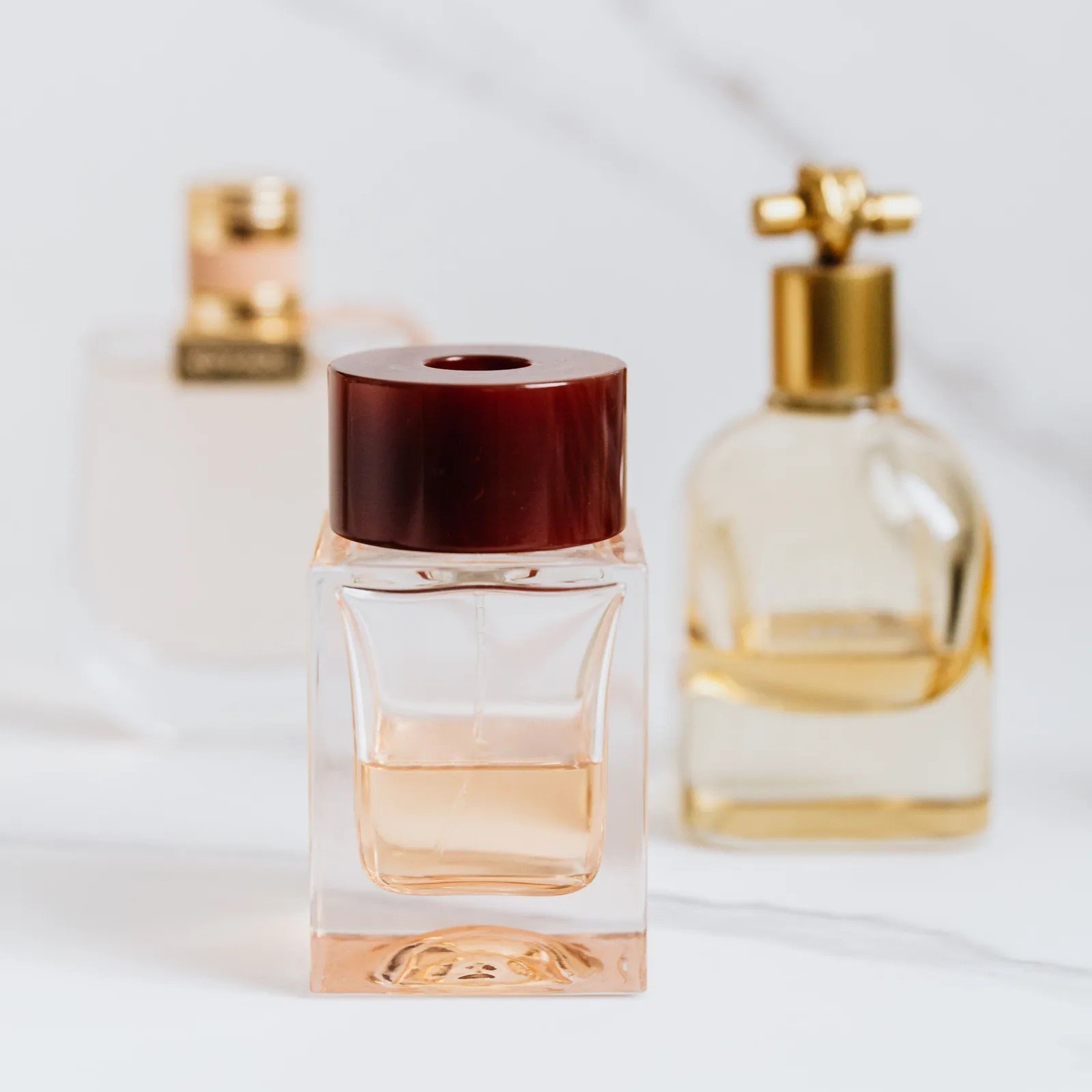 Três frascos de perfume elegantes sobre superfície de mármore