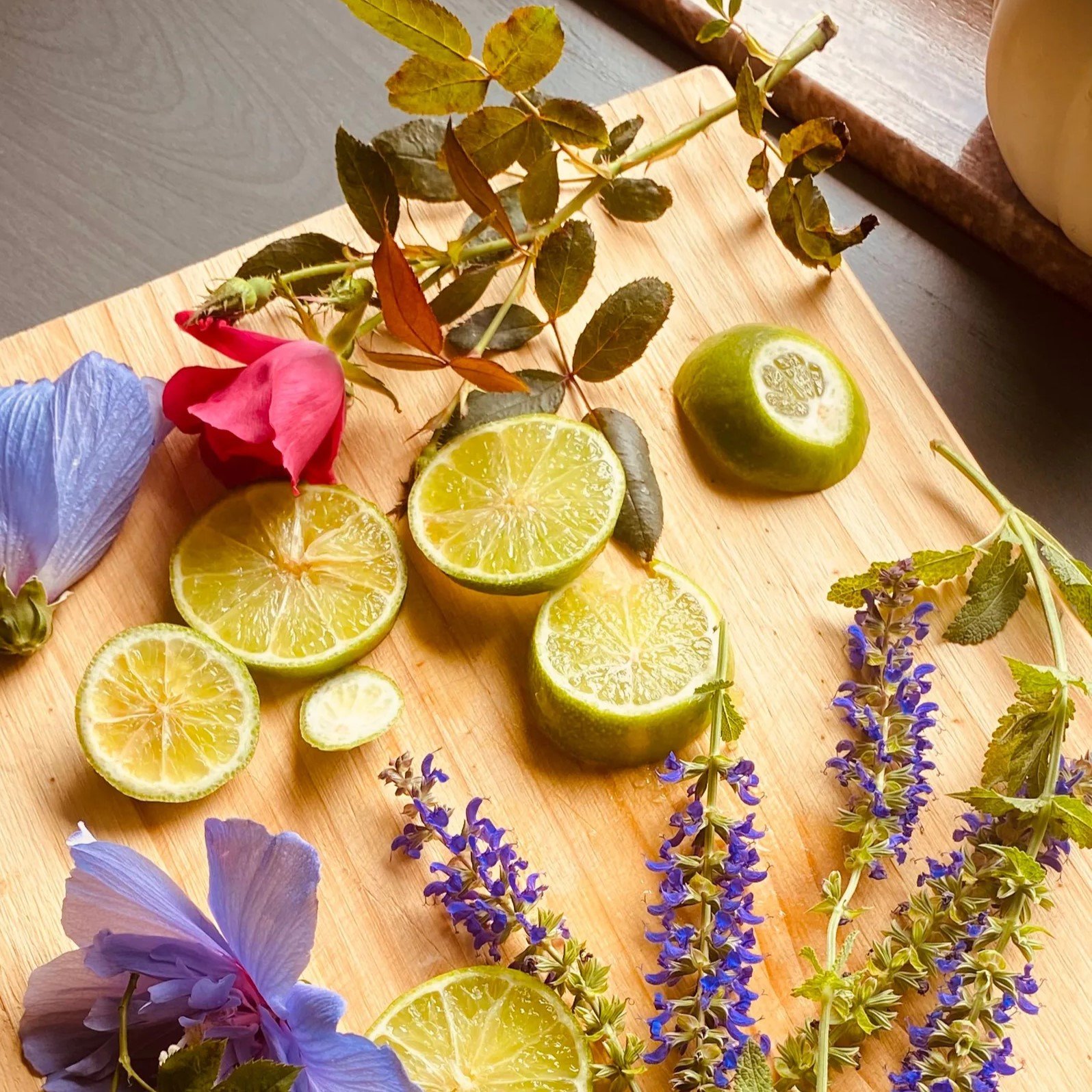 Fatias de limão e flores roxas sobre tábua de madeira que representam notas cítricas