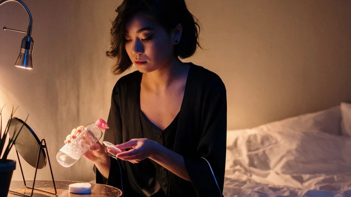 mulher aplicando skincare à noite